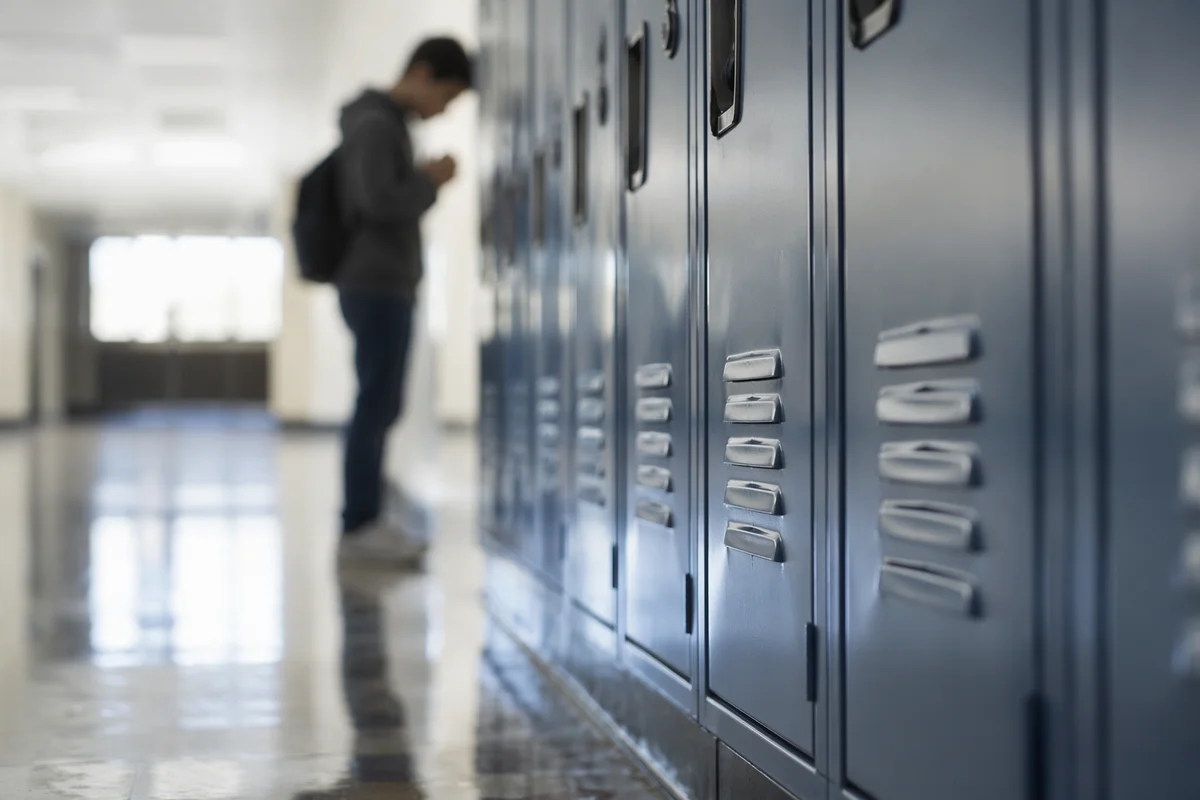 High School Student Praying by Lockers