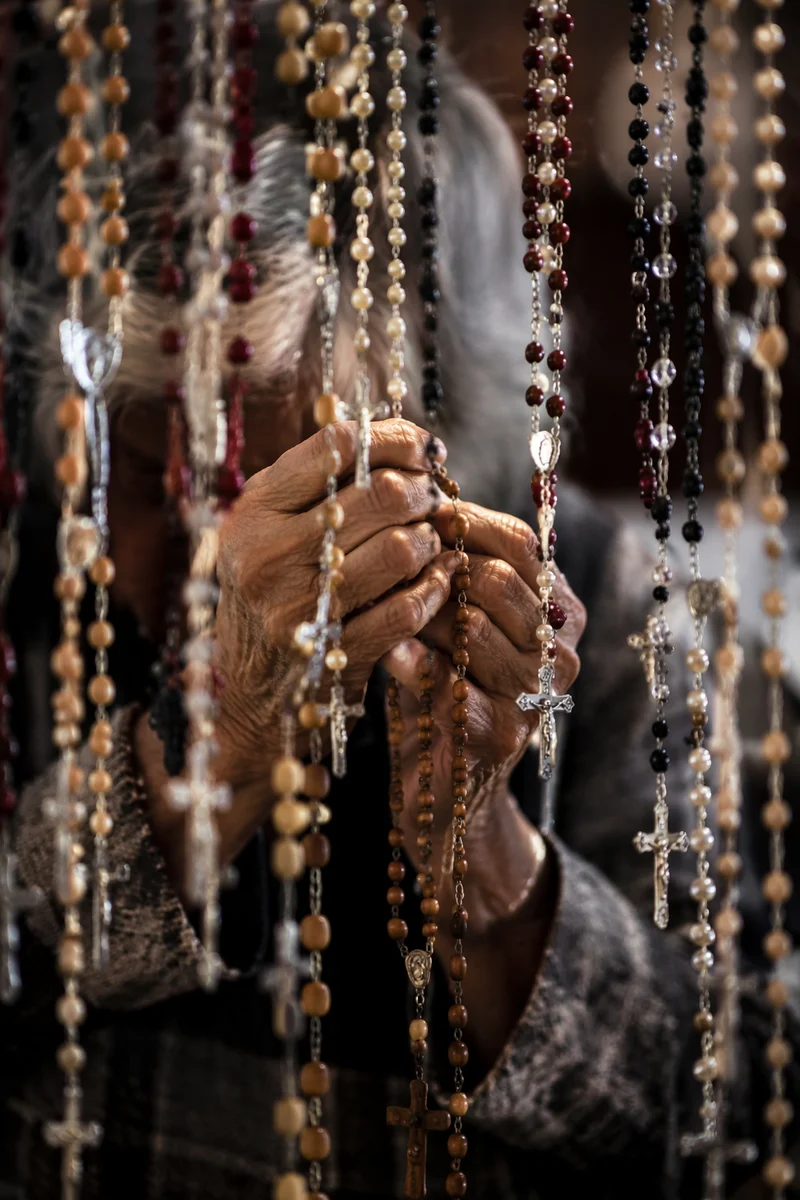Hispanic Grandmother Holding Rosary in Prayer