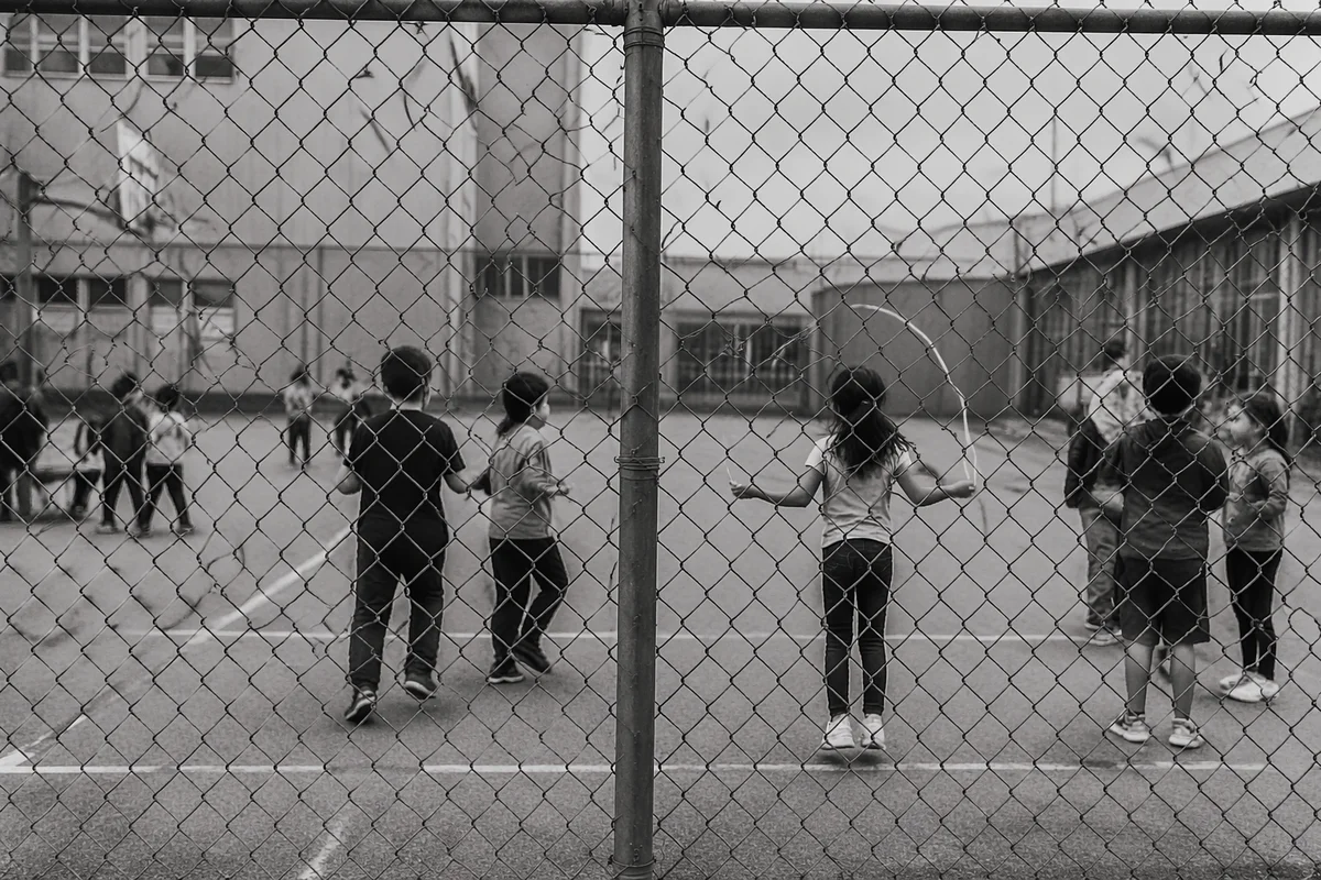 Children Playing Behind School Playground Fence