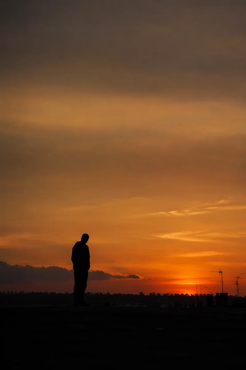 Solitary Silhouette Beneath Dramatic Sunset Sky