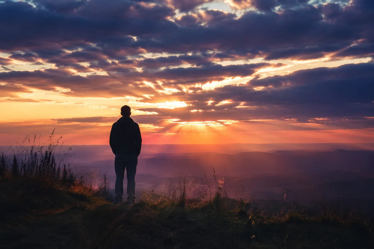 Silhouetted Figure in Prayerful Sunset Reflection