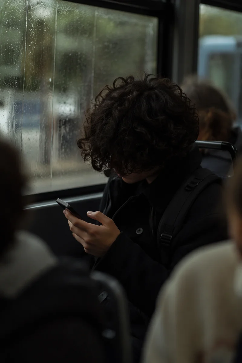 Teen Student Browsing Phone on Rainy Commute