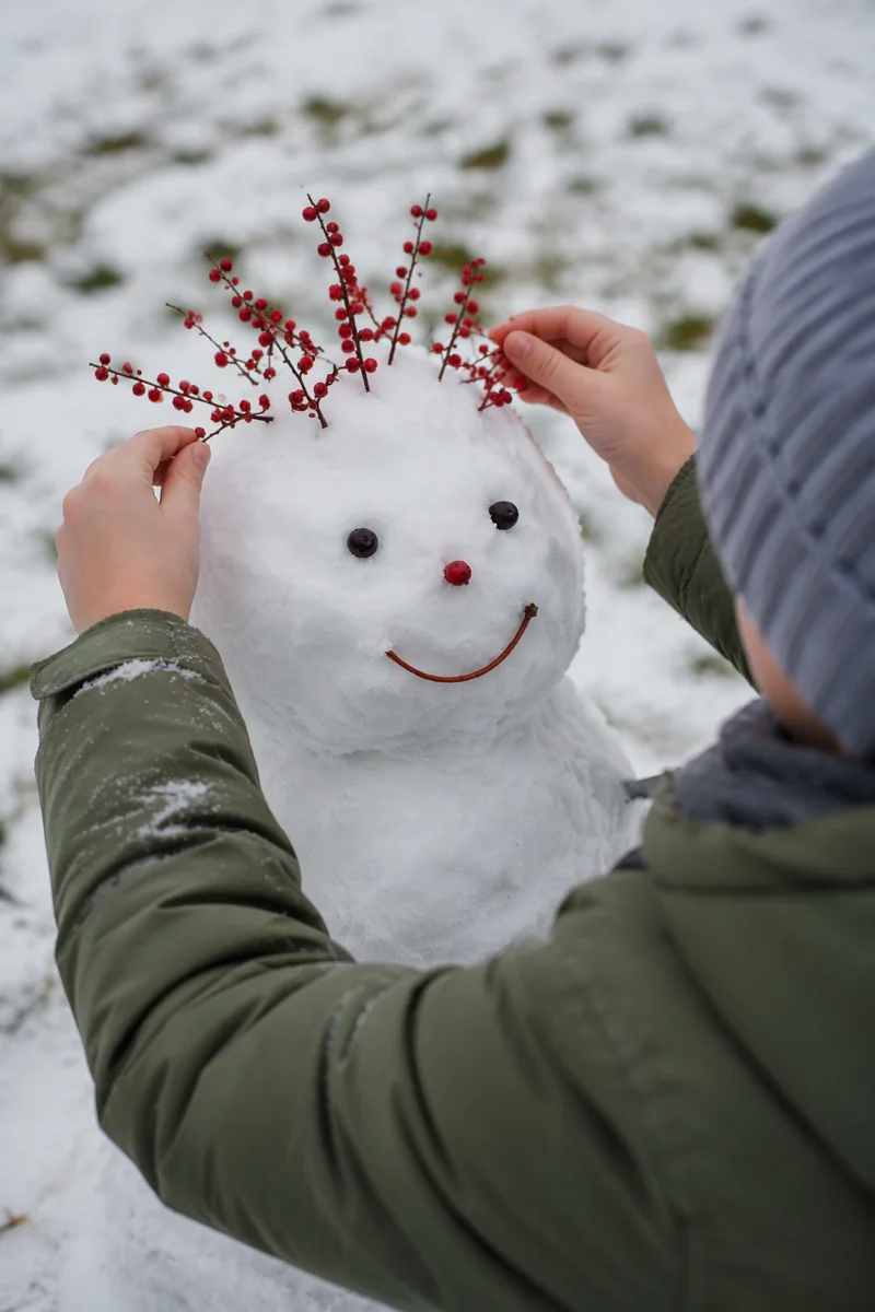 Child Decorating Small Backyard Snowman