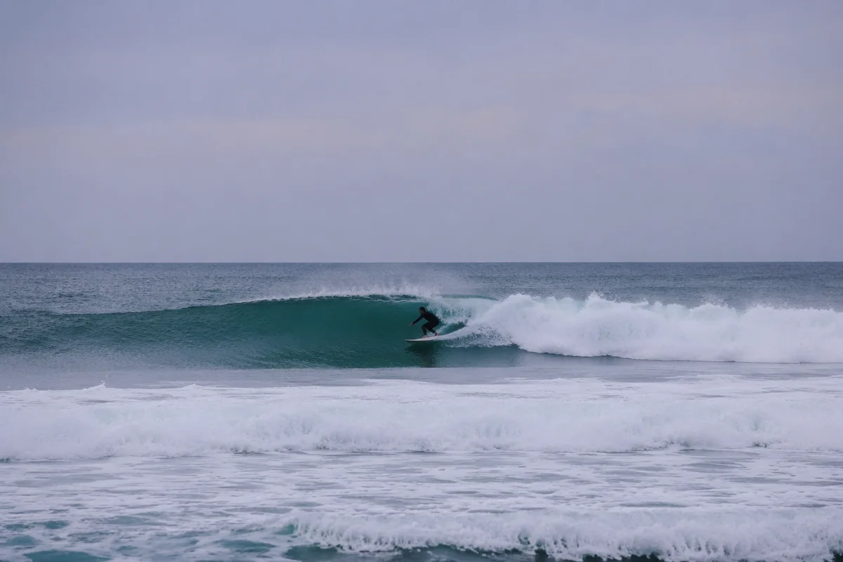 Distant Surfer Riding Teal Ocean Wave