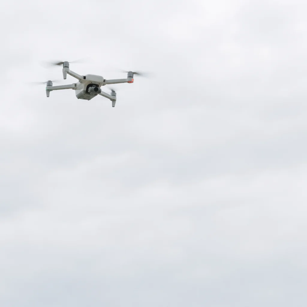 White Drone Hovering in Overcast Sky