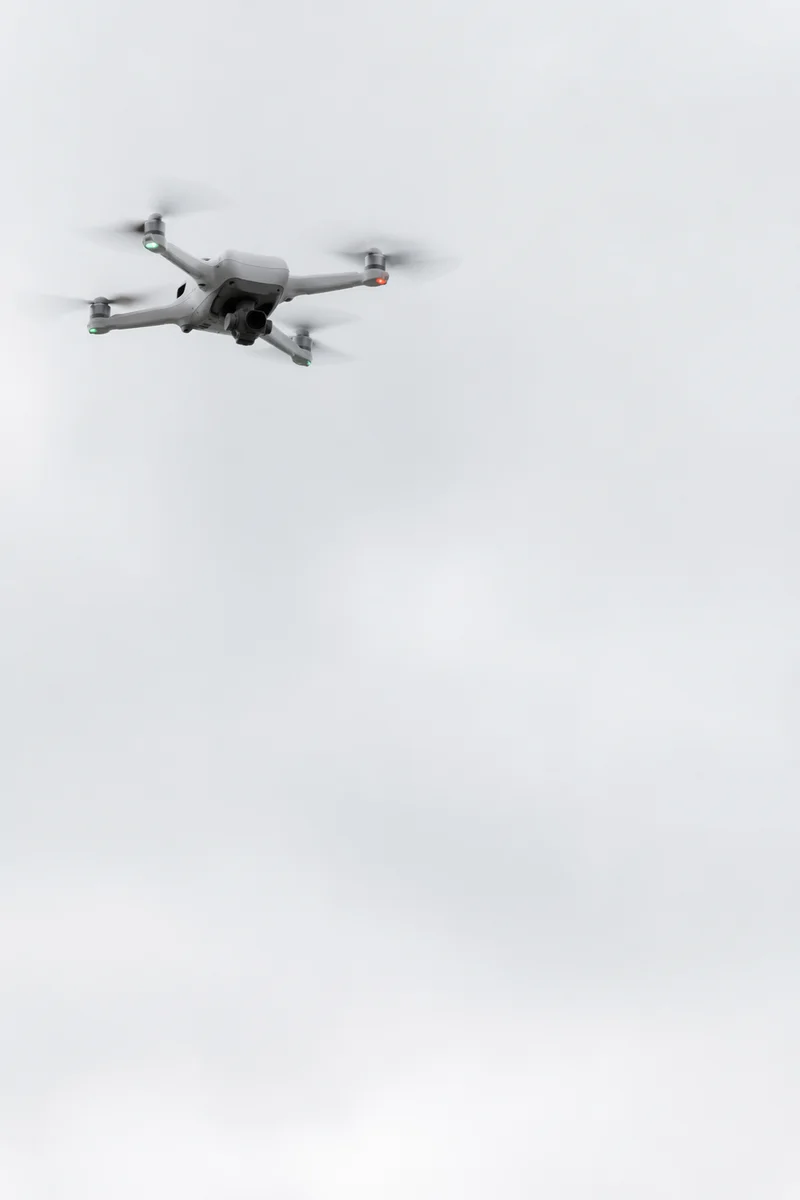 White Drone Hovering in Overcast Sky