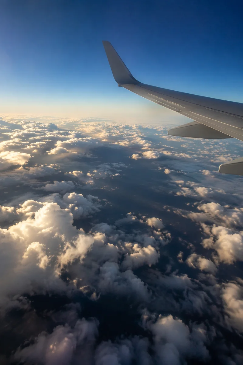 Airplane Wing Above Sunlit Cloudscape