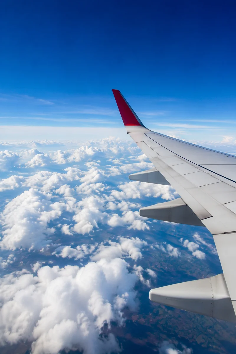 Airplane Wing Above Sunlit Clouds