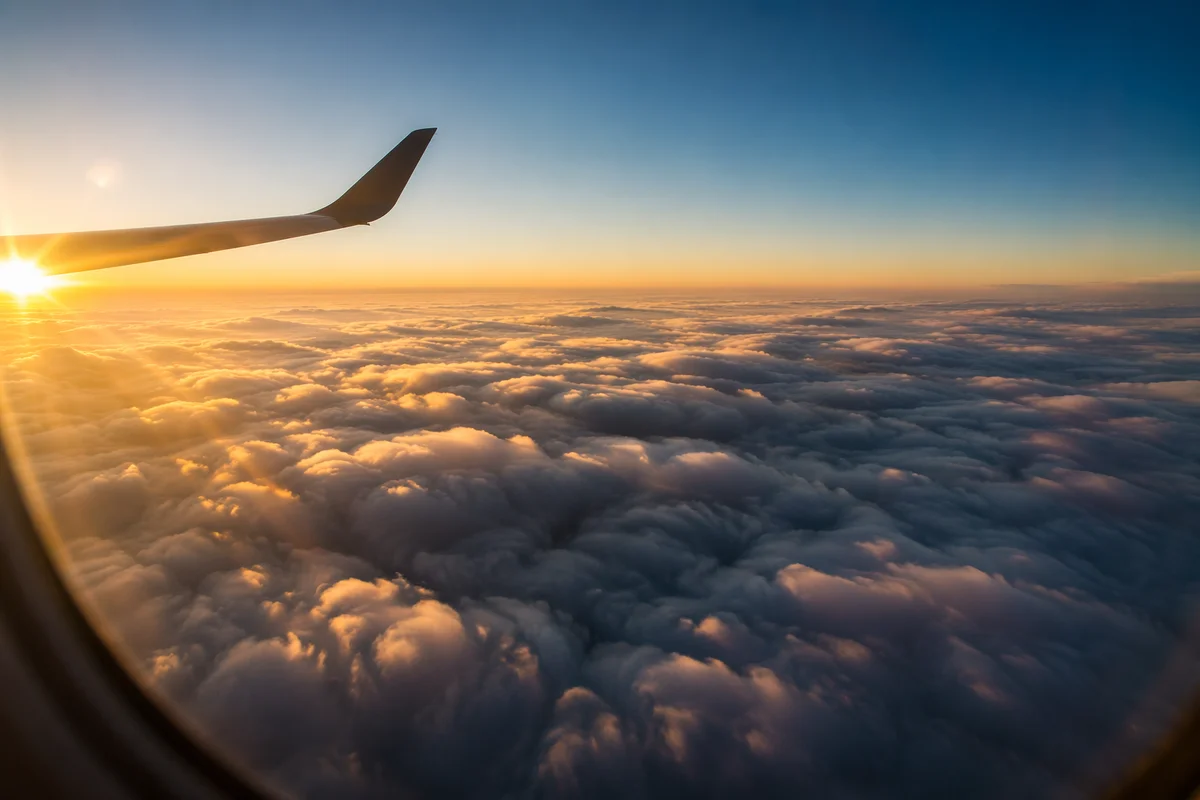 Airplane Window View Above Golden Clouds