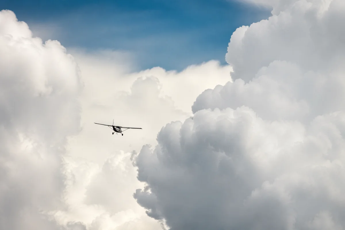 Airplane Flying Through Towering Clouds