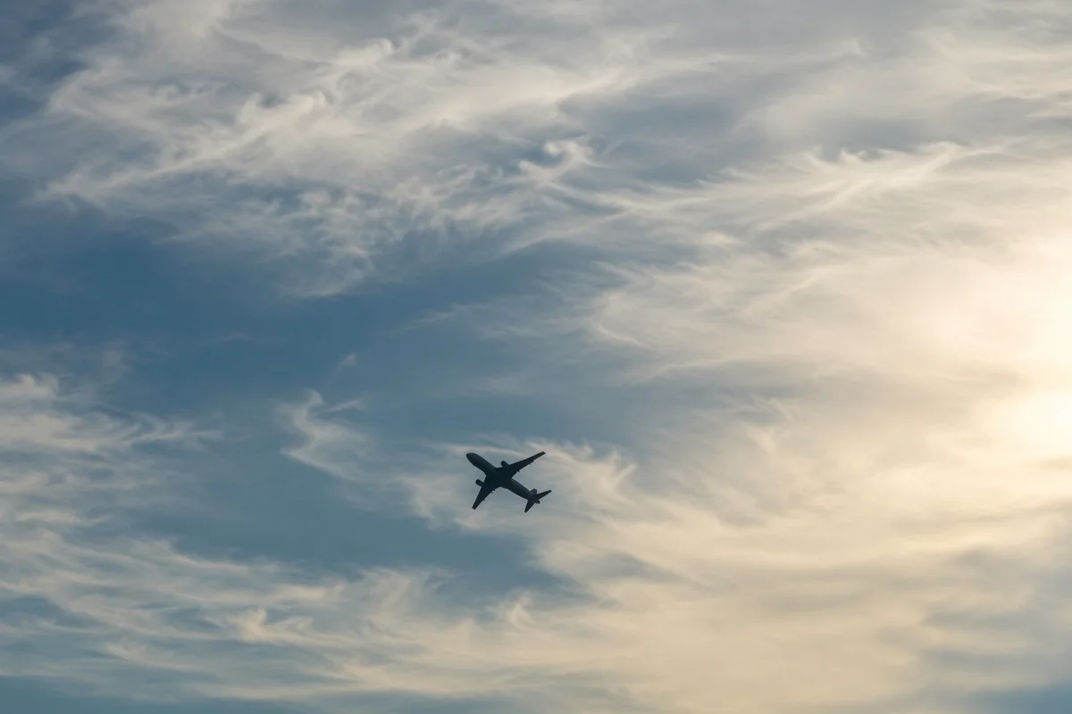 Airplane Silhouette Through Wispy Clouded Sky