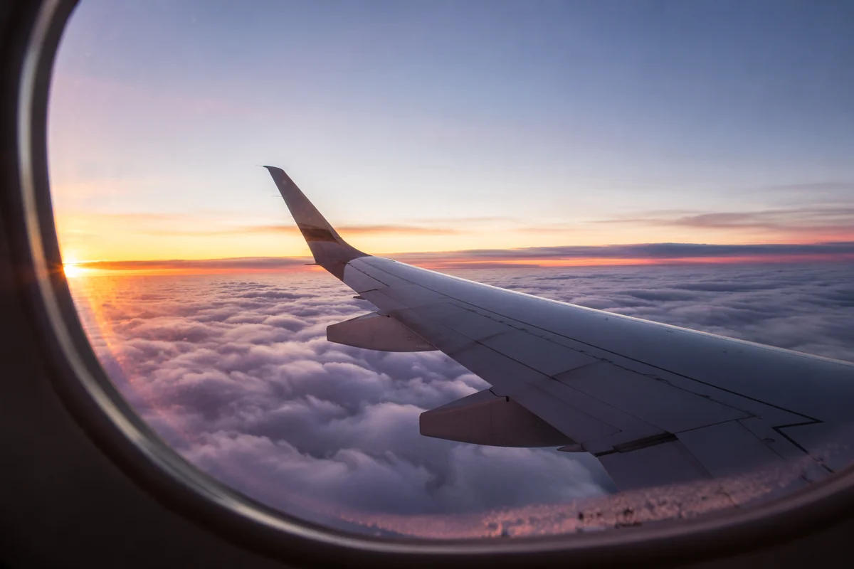 Airplane Wing Above Clouds at Sunrise