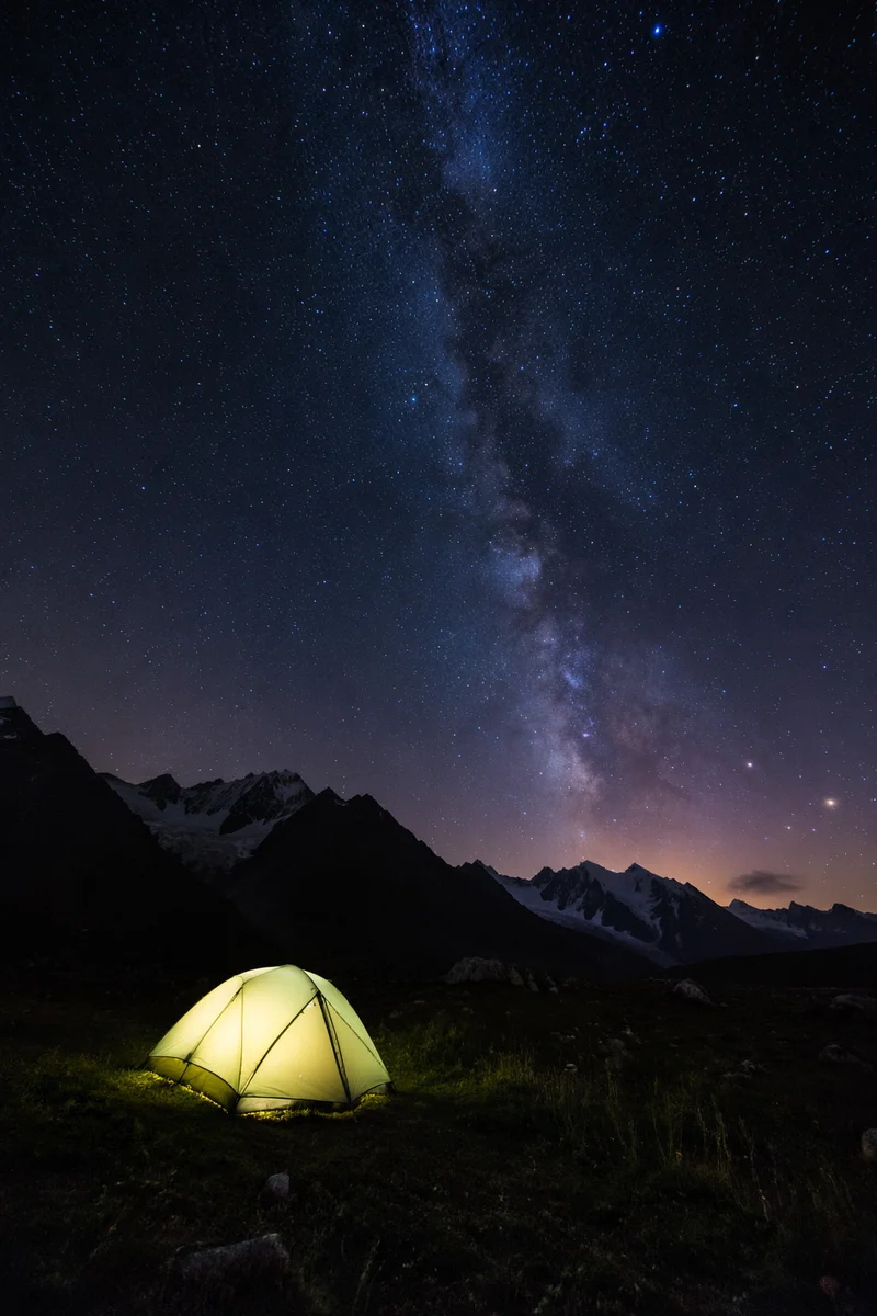 Glowing Tent Beneath Starry Alpine Mountains