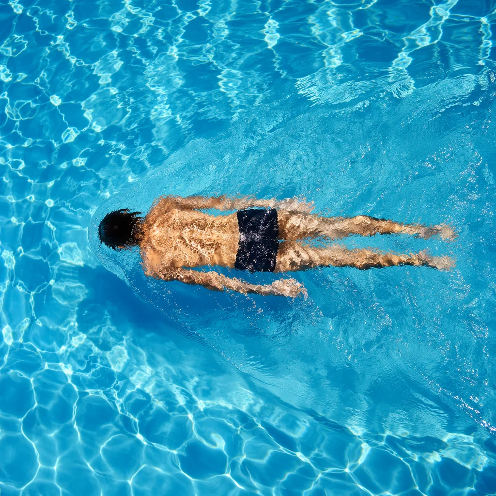 Relaxed Swimming Laps in Sunlit Pool