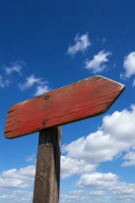 Red Wooden Arrow Pointing Toward Blue Sky
