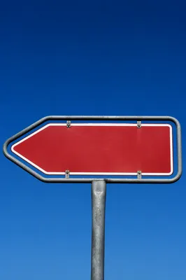 Red Left Arrow Sign Against Blue Sky