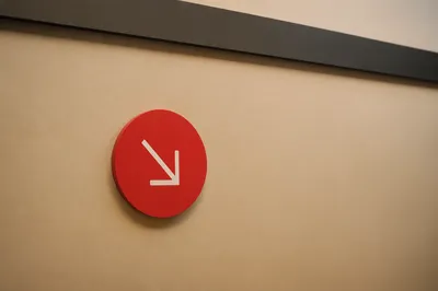Minimalist Red Arrow Sign on Beige Wall