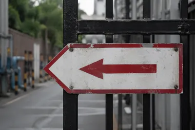 Red Arrow Direction Sign on Weathered Gate
