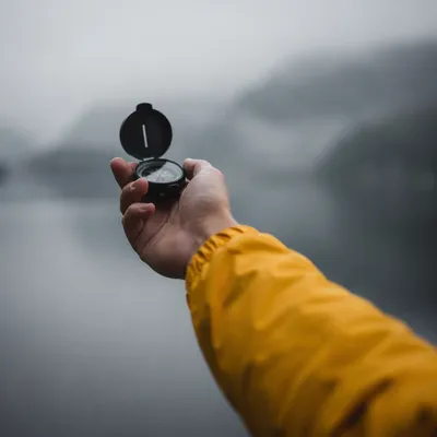 Hand Holding Compass in Misty Horizon