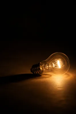 Glowing Light Bulb in Abstract Darkness