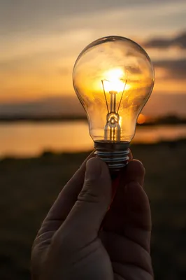 Glowing Light Bulb Held at Sunset