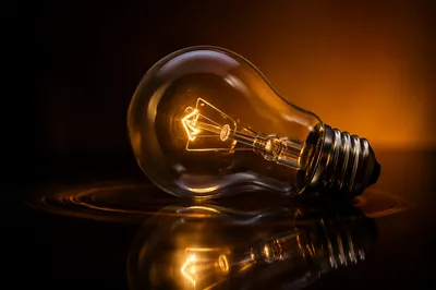 Glowing Light Bulb on Dark Reflection