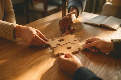 Hands Joining Wooden Puzzle Pieces in Teamwork