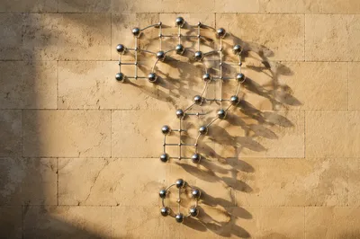 Chrome Question Mark on Sunlit Stone Wall