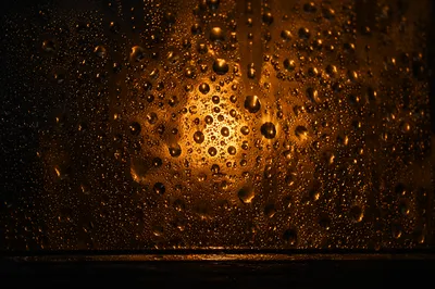 Golden Water Droplets on Dark Glass