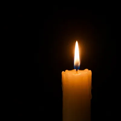 Single Candle Flame on Dark Background