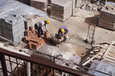 Construction Workers Handling Bricks at Busy Site