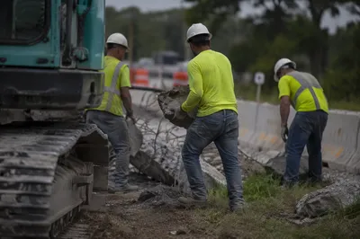 Construction Workers Clearing Roadside Concrete Debris