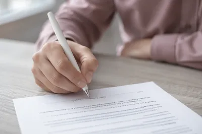 Hand Signing Business Contract on Gray Desk