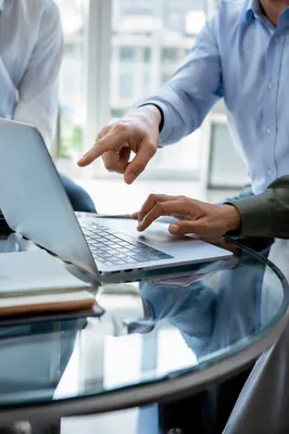 Hands Discussing Laptop in Modern Office