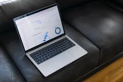 Laptop Analytics Dashboard on Charcoal Sofa