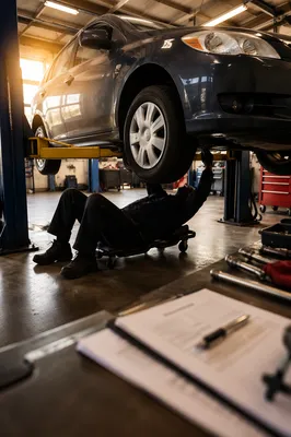 Mechanic Working Beneath Lifted Car