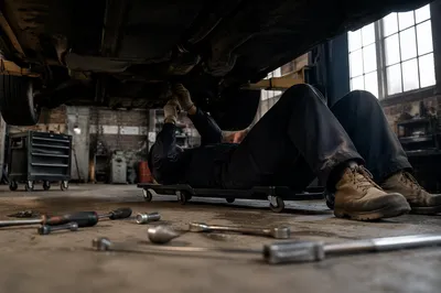 Mechanic Working Beneath Car in Repair Shop