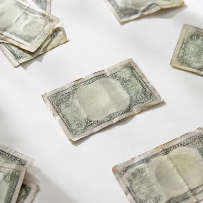 Scattered Dollar Bills on White Tabletop