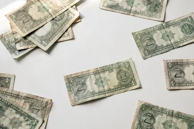 Scattered Dollar Bills on White Table