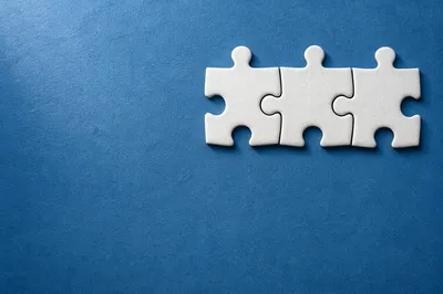 White Puzzle Pieces on Blue Teamwork Background