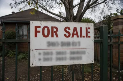 Weathered House For Sale Sign on Fence