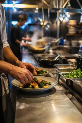 Chef Plating Dinner in Busy Restaurant Kitchen