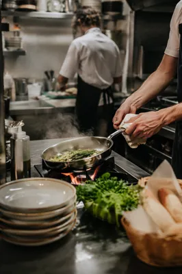 Chef Sautéing Vegetables in Busy Restaurant Kitchen