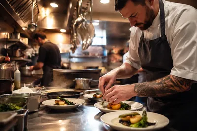 Chef Plating Dishes in Busy Restaurant Kitchen