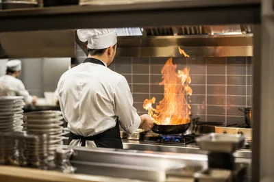 Chef Sautéing Over Flame in Restaurant Kitchen