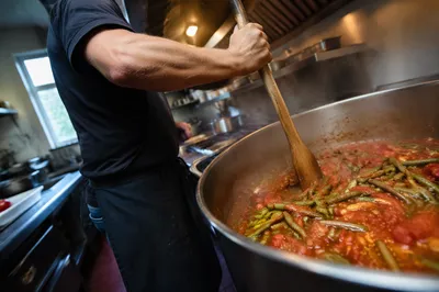 Chef Stirring Simmering Pot in Restaurant Kitchen