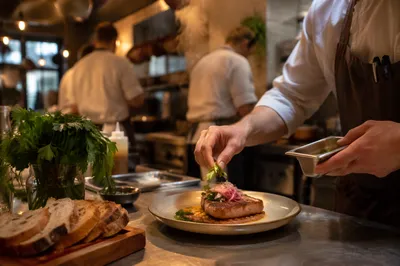 Chef Plating Dinner in Busy Restaurant Kitchen