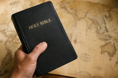 Hand Holding Bible Over Mission Map