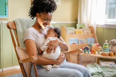 Nursery Volunteer Cradling Baby in Sunlight