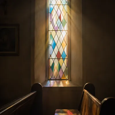 Sunlit Chapel Pews and Stained Glass